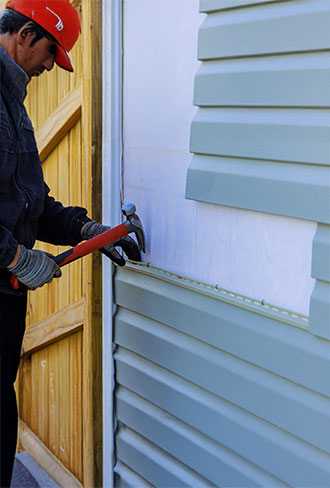 skilled technician inspecting home siding for weather related damage